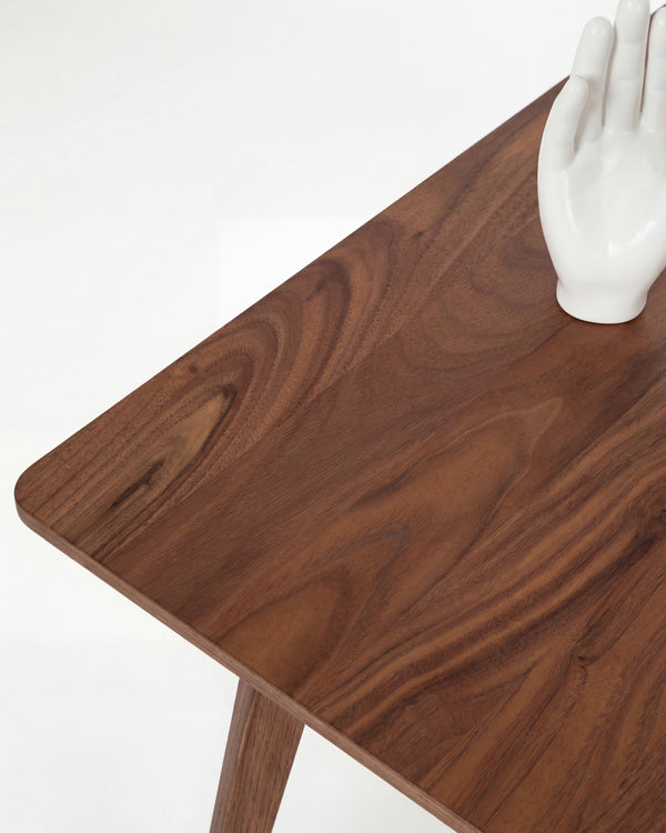 Wooden table corner with a white ceramic hand sculpture.