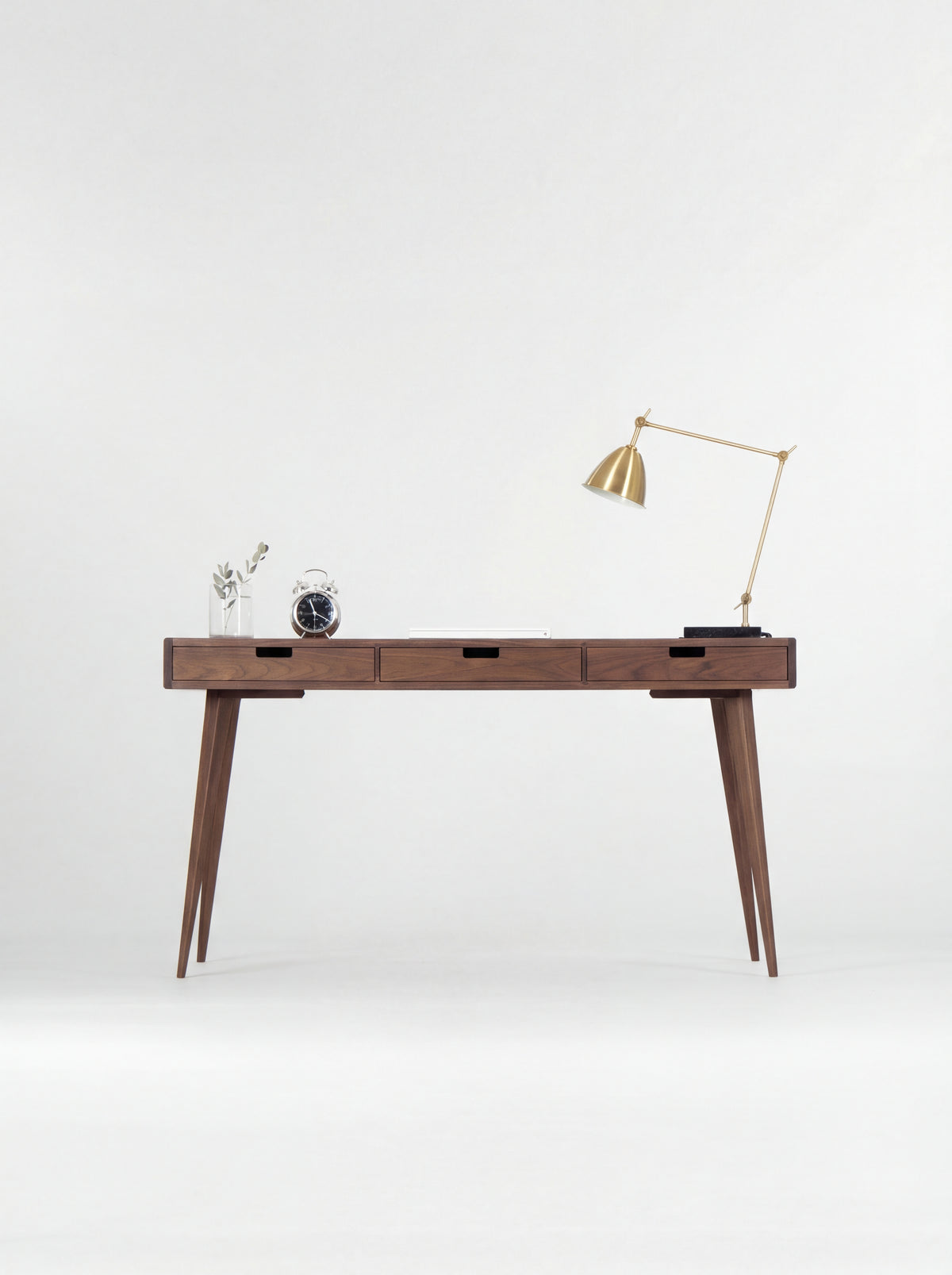 Front view of the HEIM 140 desk in walnut wood, showing three closed drawers with rectangular cut-out grips