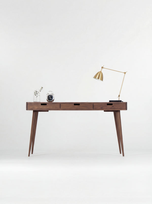 Front view of the HEIM 140 desk in walnut wood, showing three closed drawers with rectangular cut-out grips