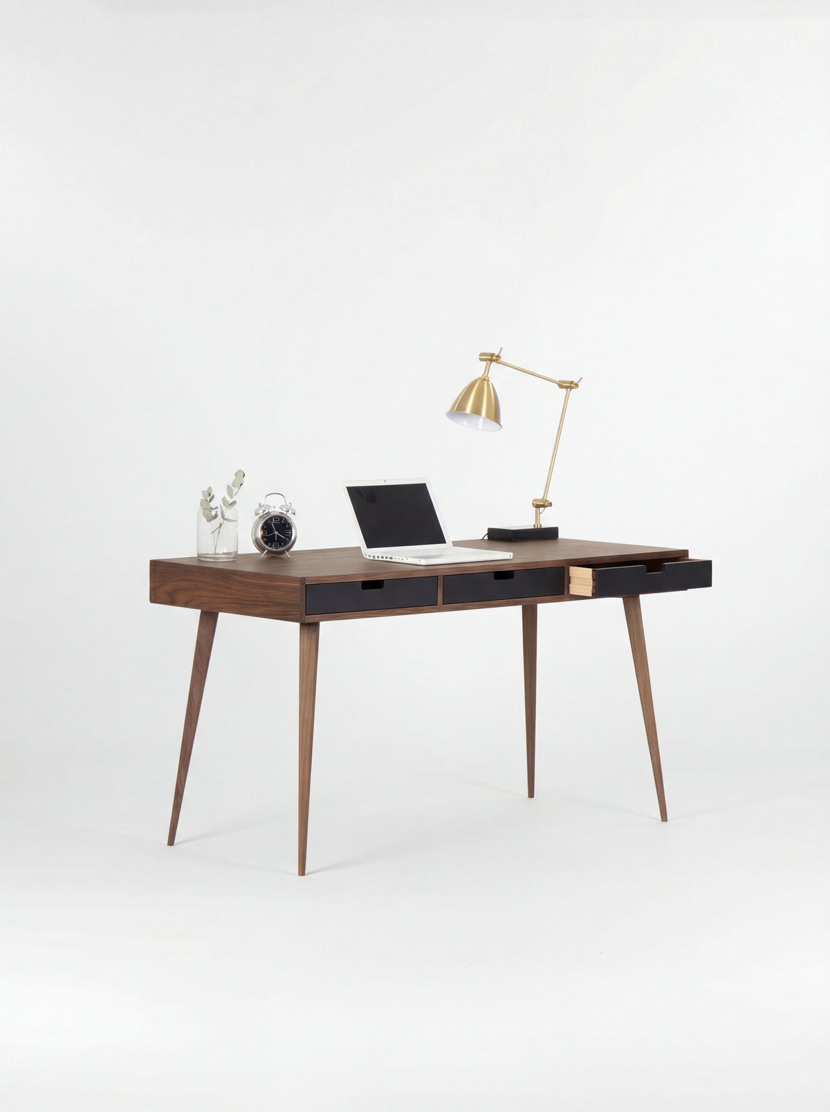 HEIM 140 desk in walnut wood with three black drawer fronts, the right drawer open and a clock on top