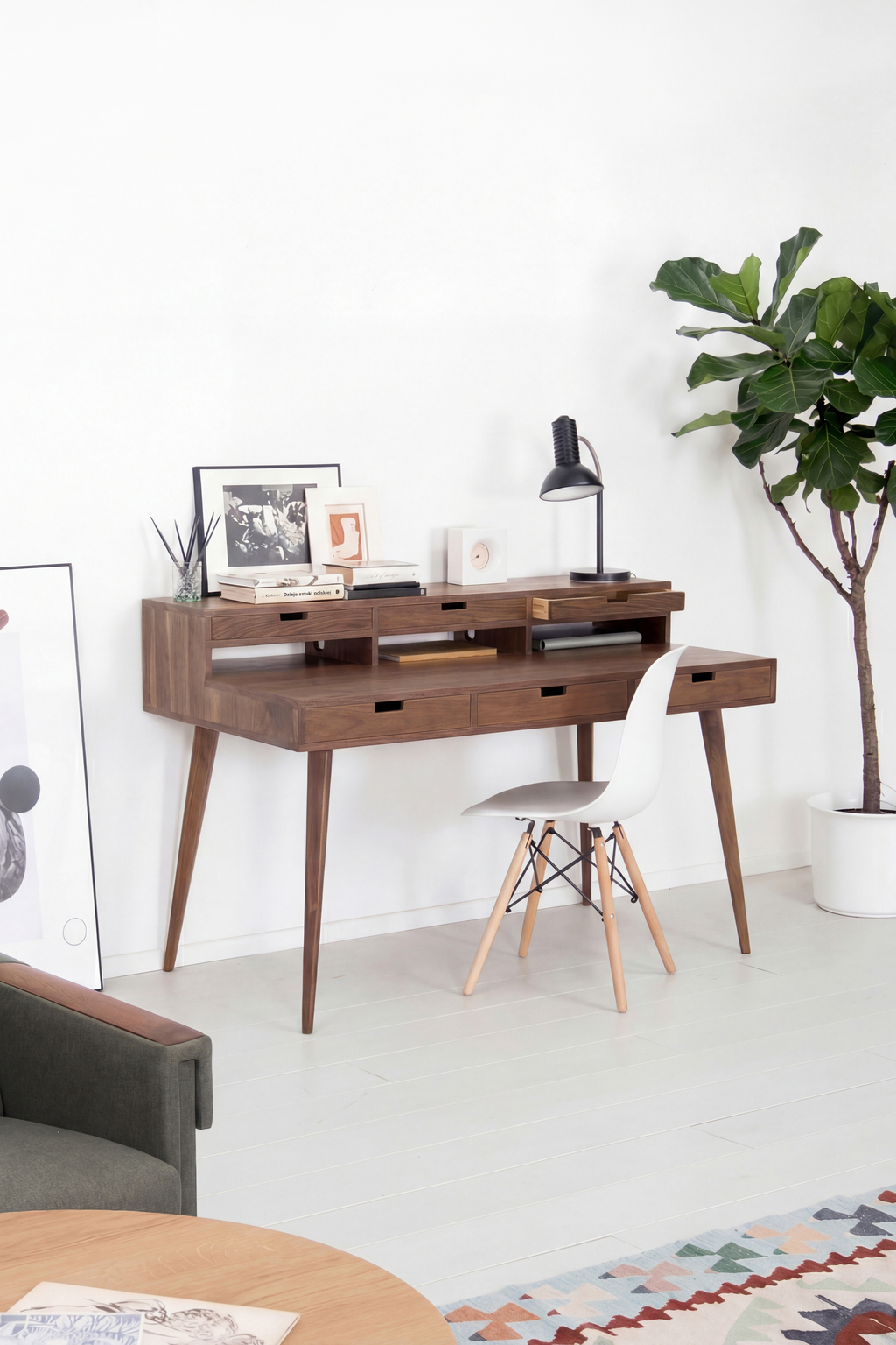 HEIM 140 writing desk with hutch in solid walnut, angled in a living room with a white shell chair and books