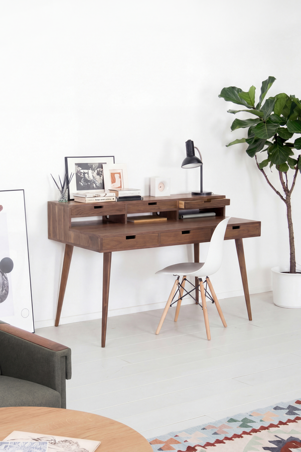 HEIM 140 writing desk with hutch in solid walnut, angled in a living room with a white shell chair and books